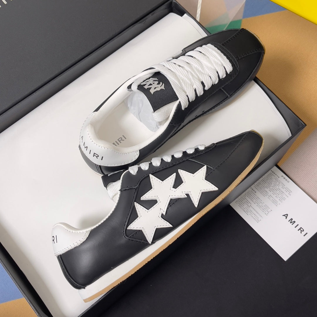 Black leather sneakers in a box with white star appliques and white lace-up front