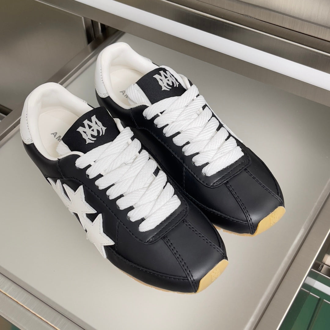 Pair of black leather sneakers with white laces and star patch on the sides