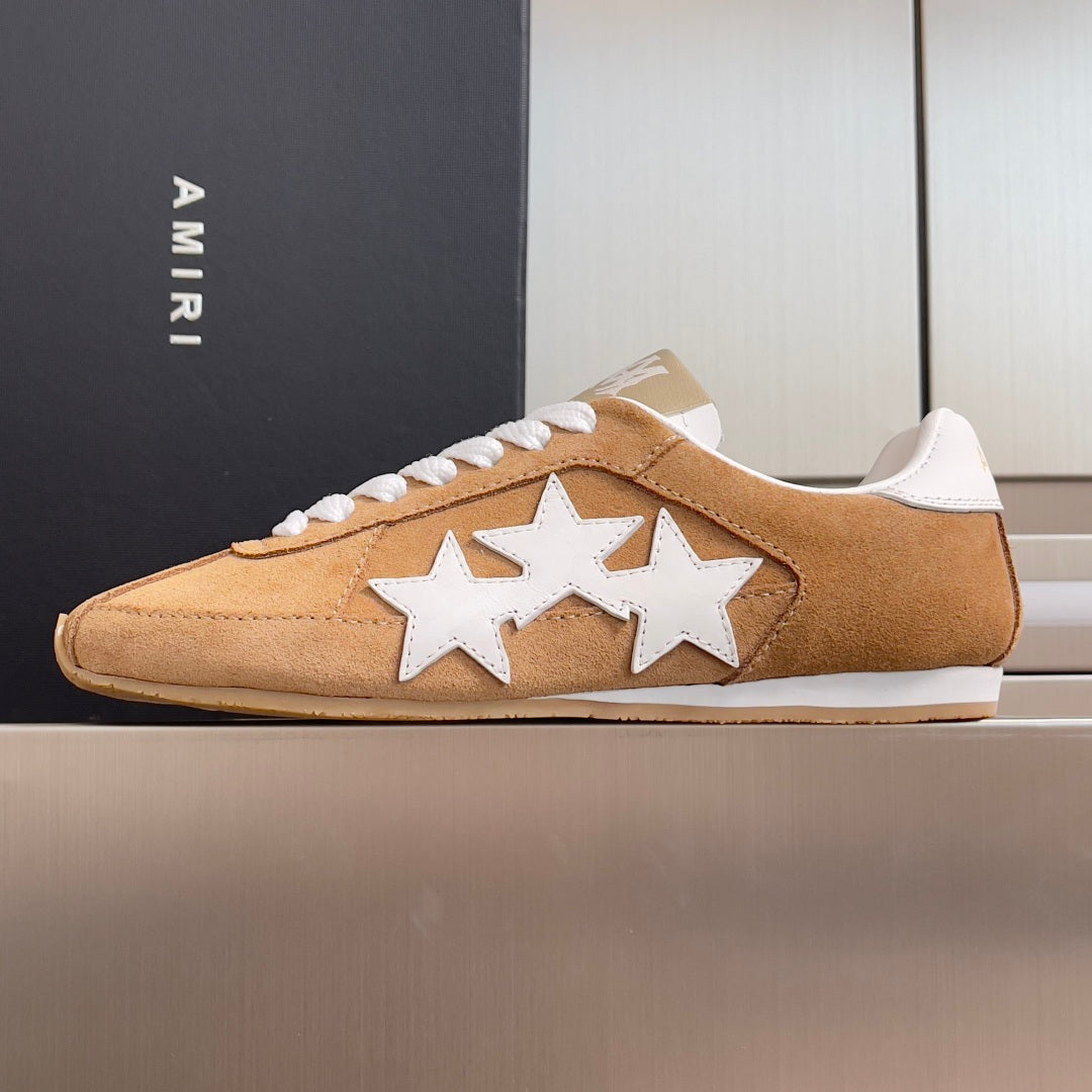 Tan suede sneakers with white star appliques and white lace-up front