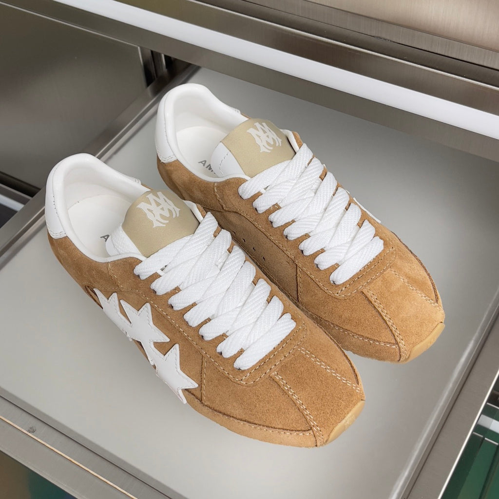 Pair of tan suede sneakers with white laces and star detail on the side