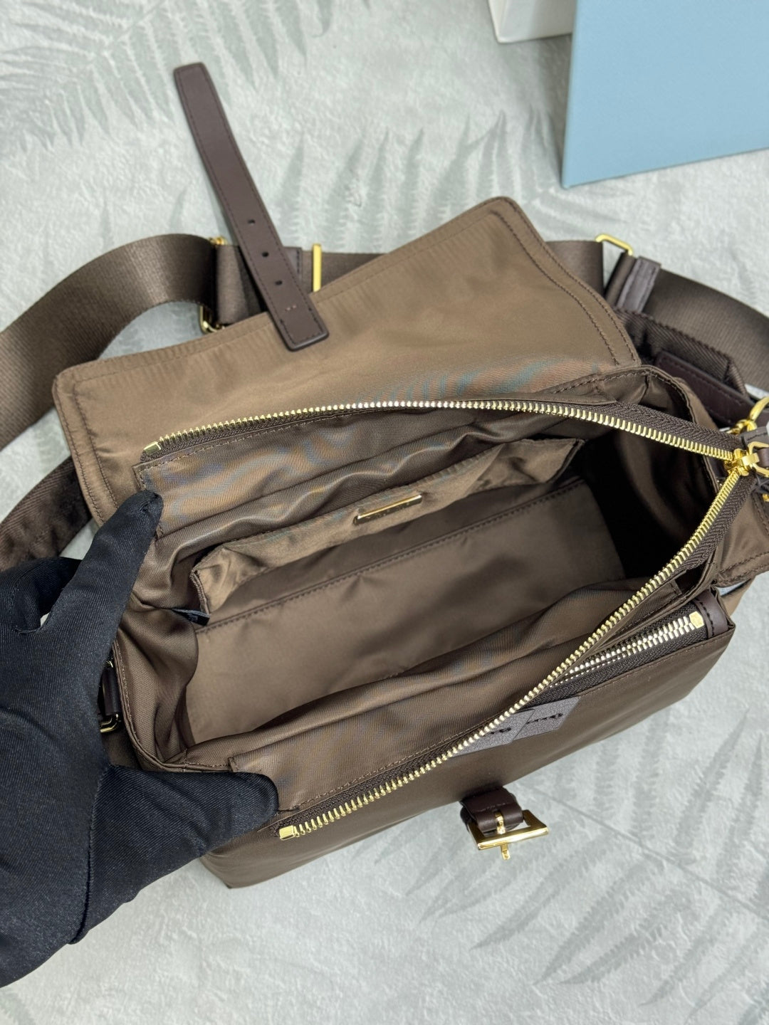 Open taupe-brown Prada bag showing interior and zip pockets with gold zippers