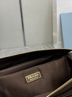 Prada logo patch on dark brown bag with gold zipper and visible stitching
