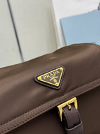 Prada logo patch on taupe-brown flap bag with gold-tone buckle hardware