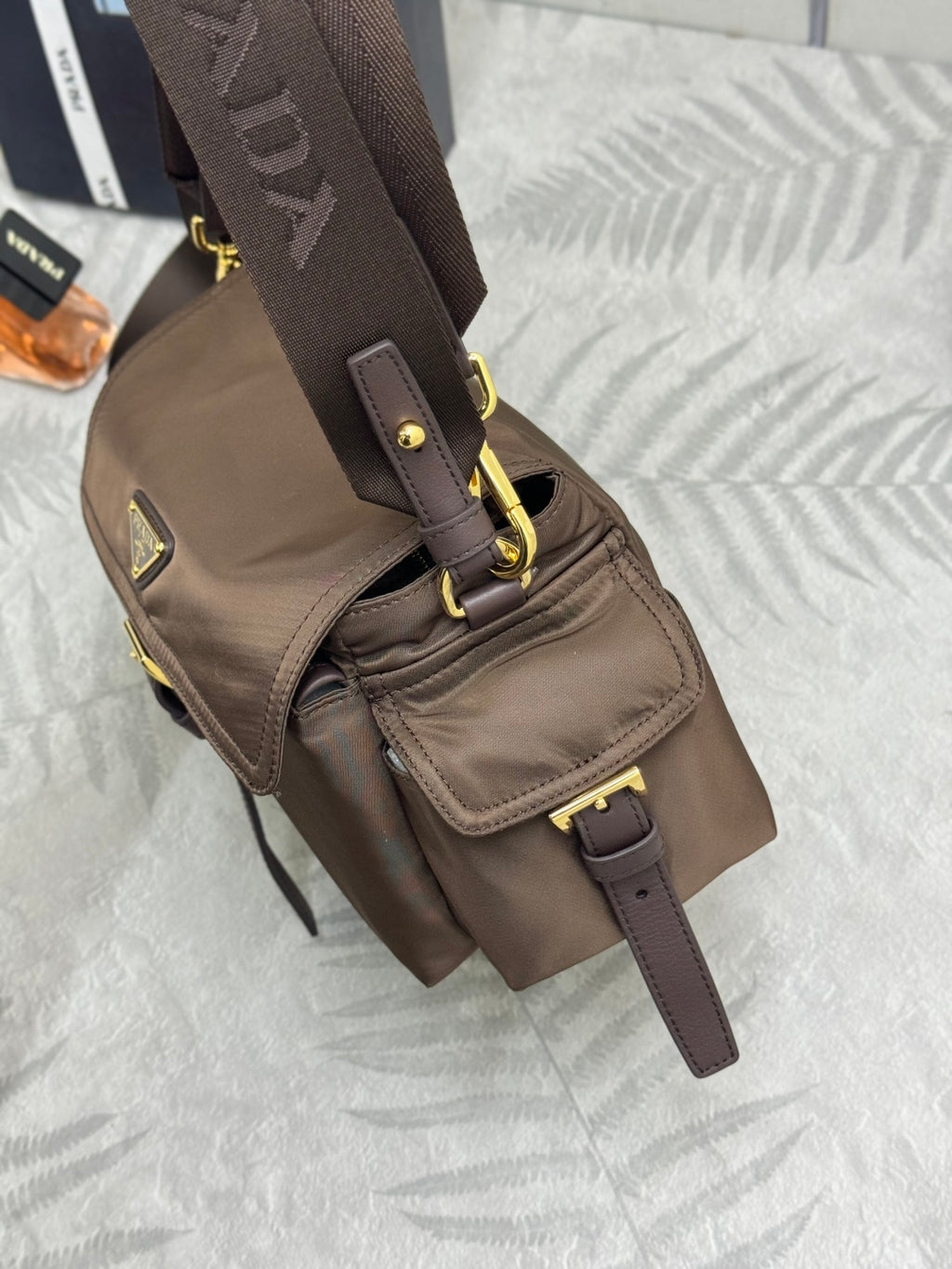 Prada mini crossbody bag in dark brown with front flap and adjustable strap