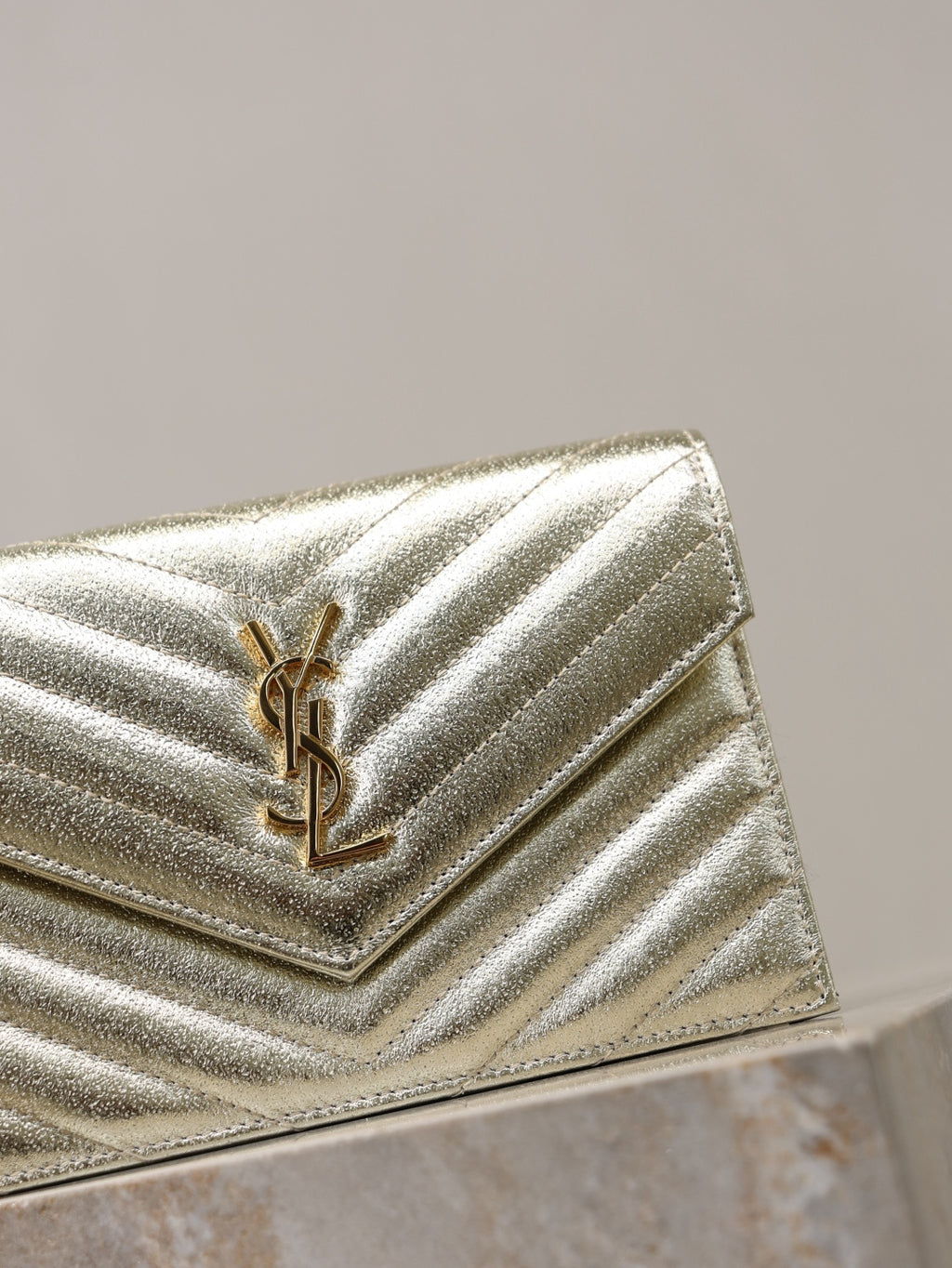 YSL metallic gold flap bag close-up with YSL logo on chevron quilting