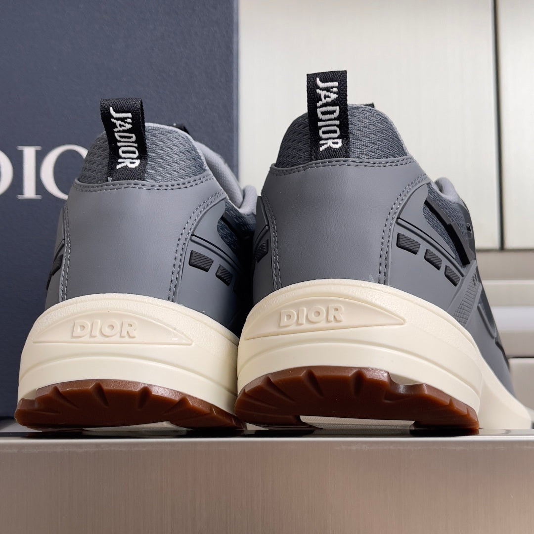 Unisex Dior sneakers with blue-gray uppers, branded heel tabs, and off-white soles.