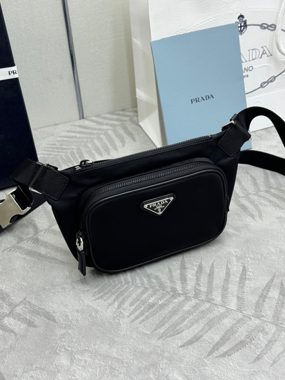Black Prada crossbody bag, angled side view with zip closure and triangular logo tag.