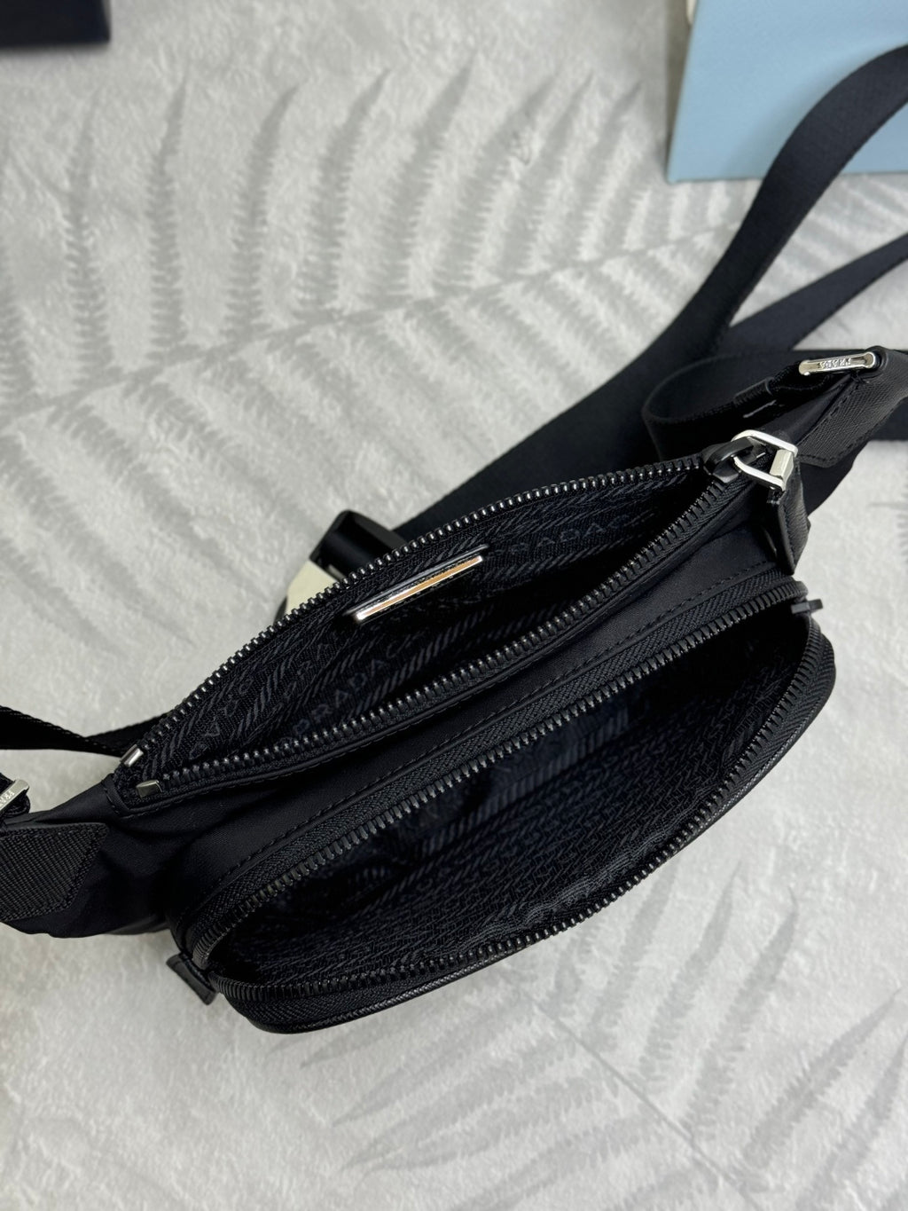 Black Prada crossbody bag close-up of dual zippers and smooth leather trim.