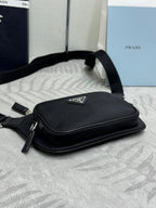 Black Prada crossbody bag lying flat, single top zip and small logo patch.