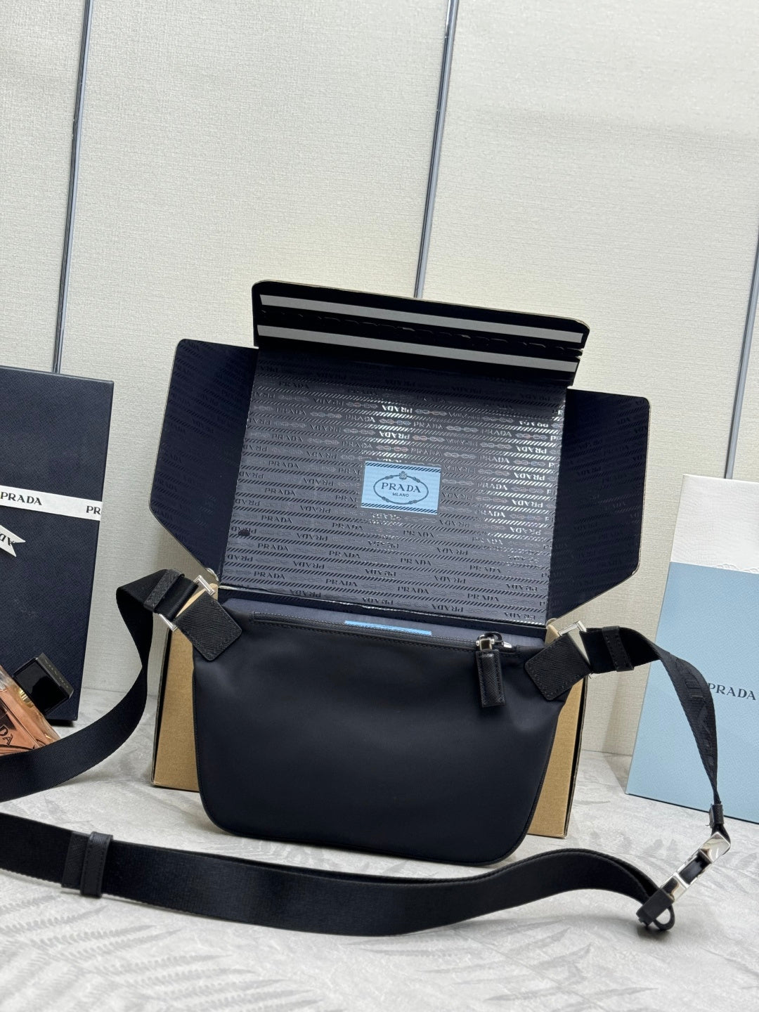 Black Prada crossbody bag, side view with adjustable strap and front zip compartment.