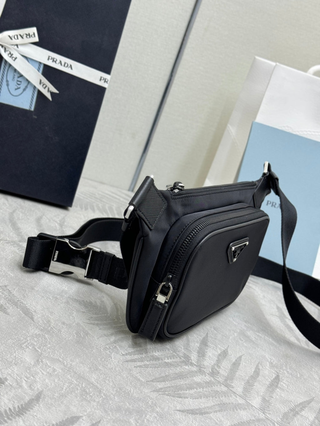 Black Prada crossbody bag, corner view with textured front panel and adjustable strap.