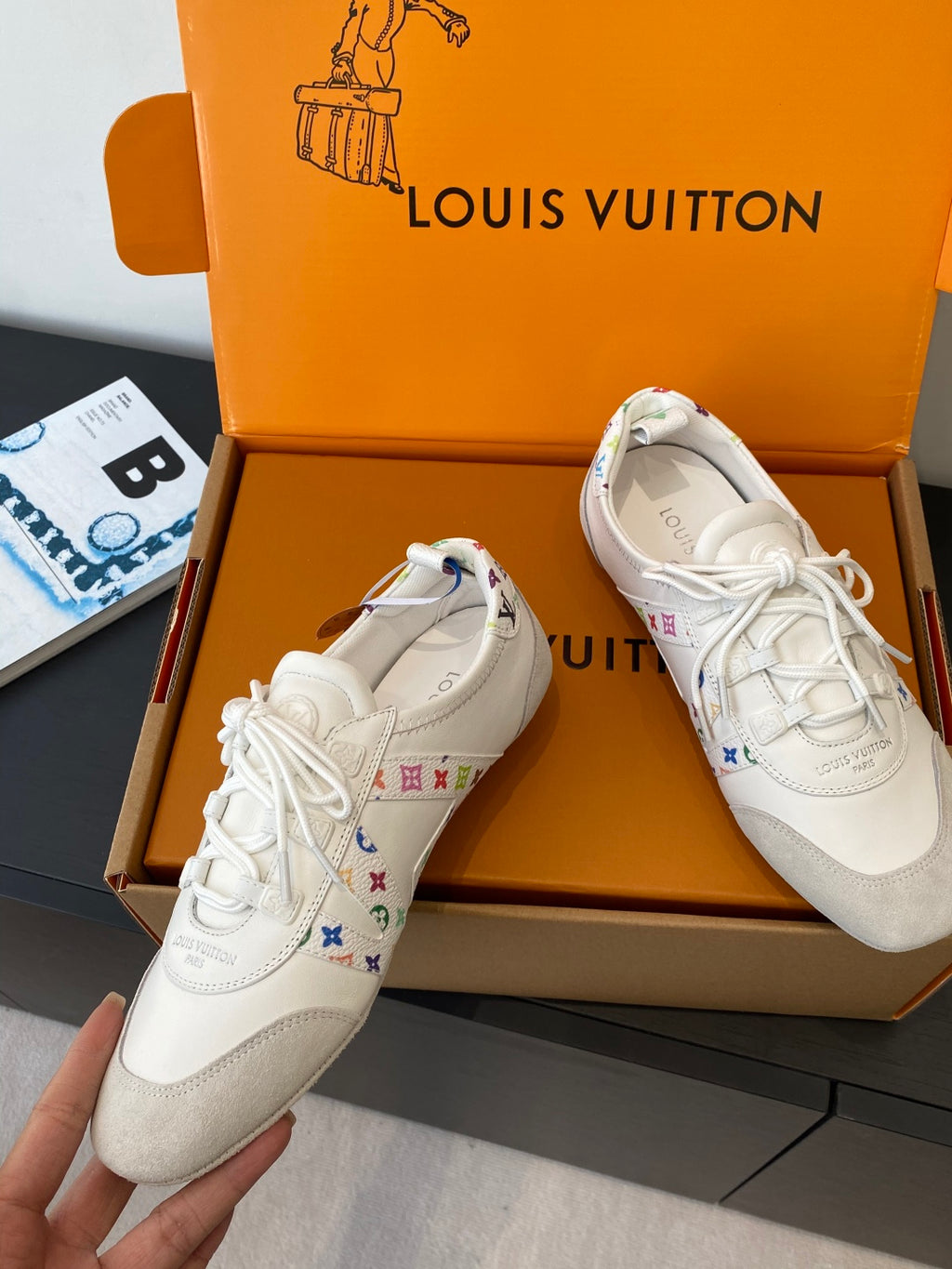 Pair of white unisex sneakers with multicolor logo detail on the side