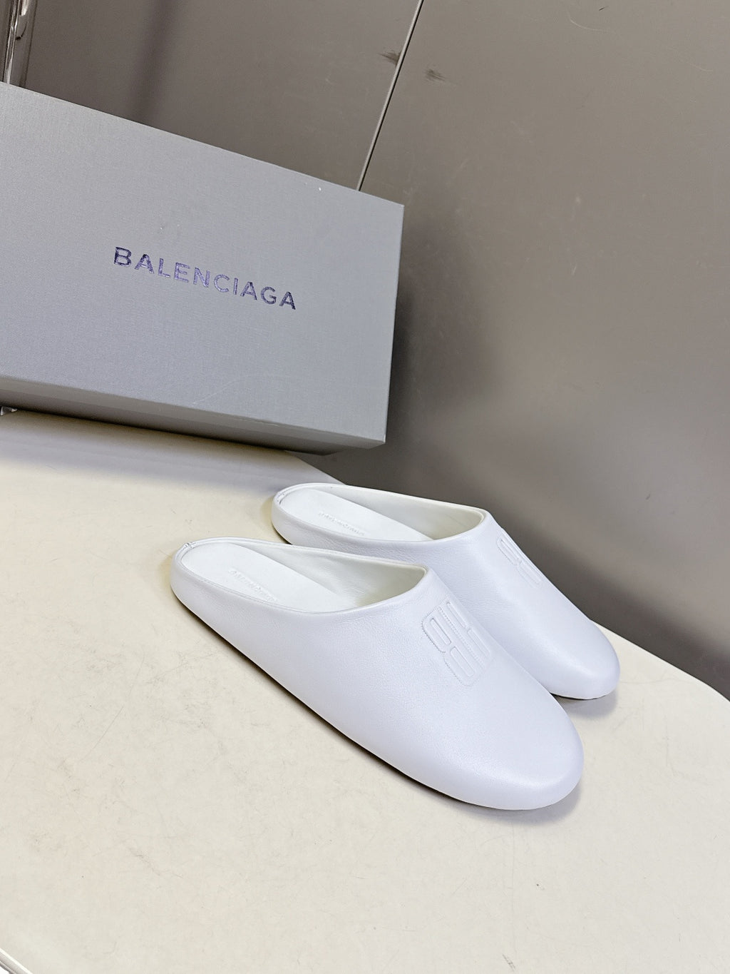 White slide sandals with wide strap and embossed logo on upper