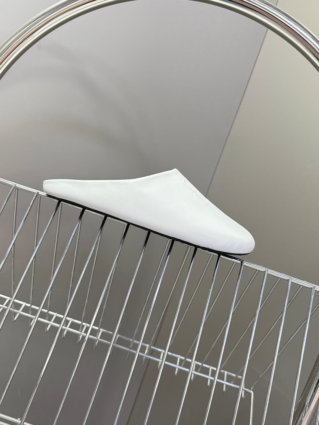 White slide sandal on wire rack with curved toe profile