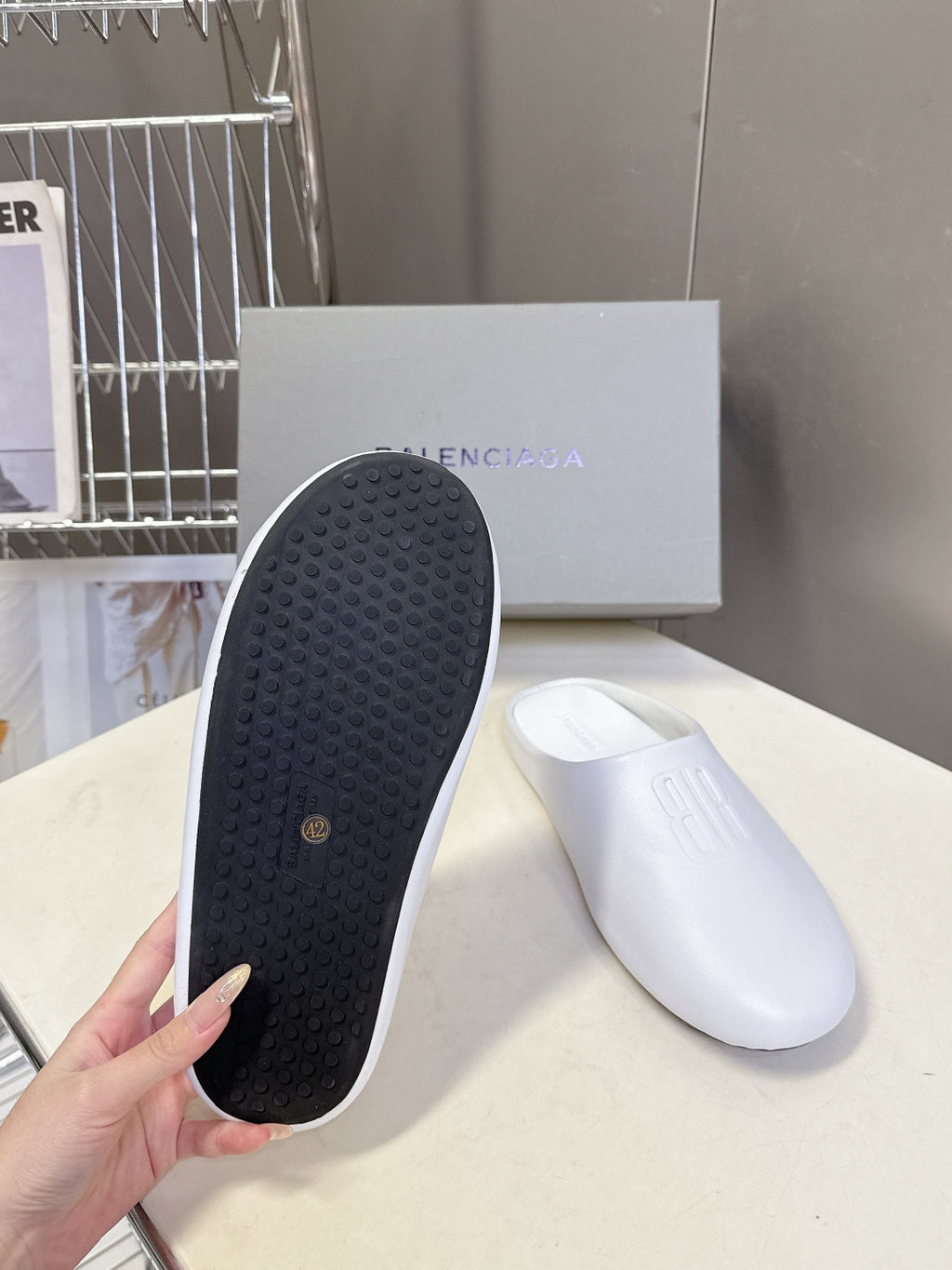 White slide sandals with textured rubber outsole and embossed logo top