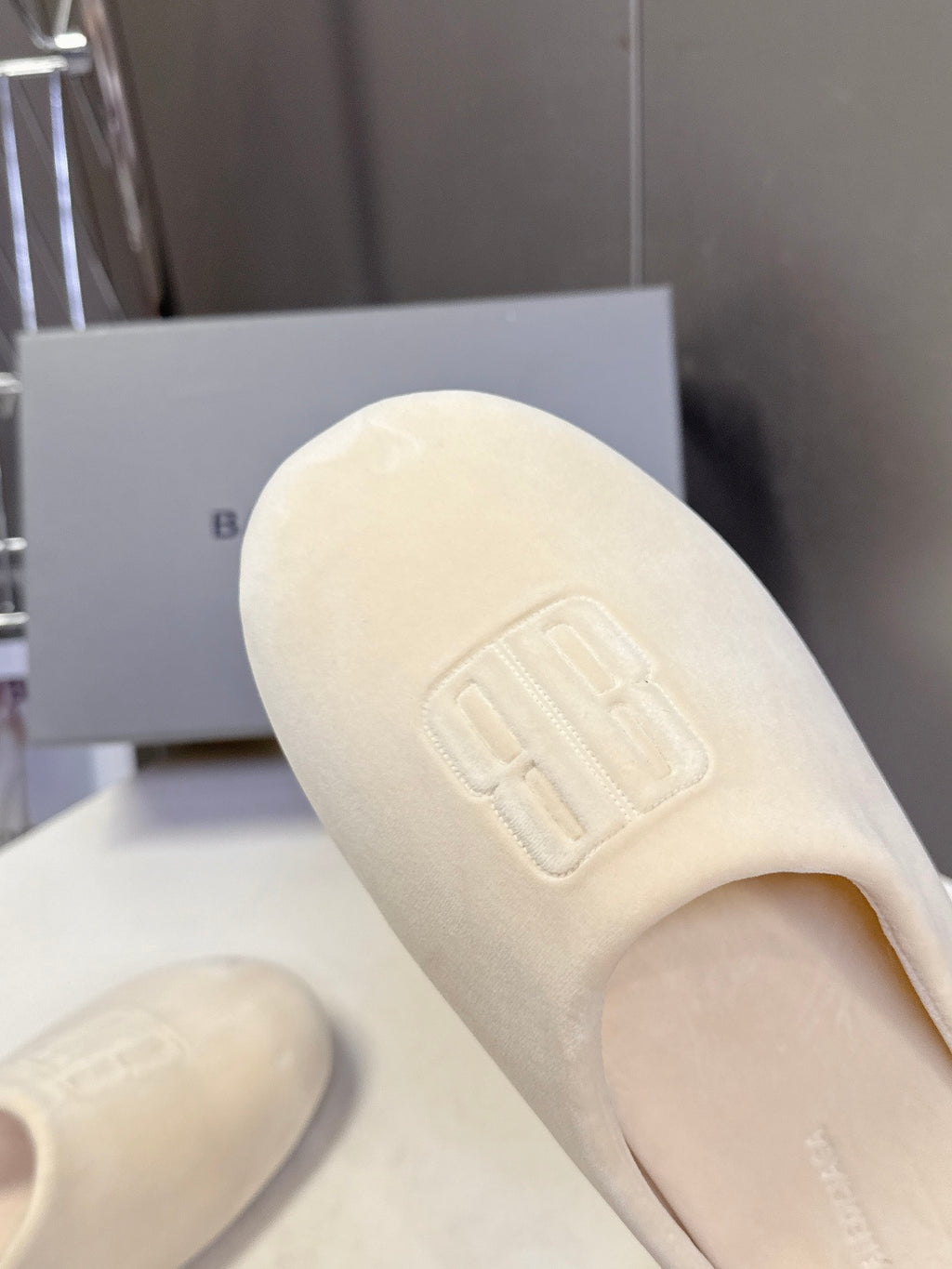 Balenciaga slide sandal, light beige, close-up of embossed logo on top