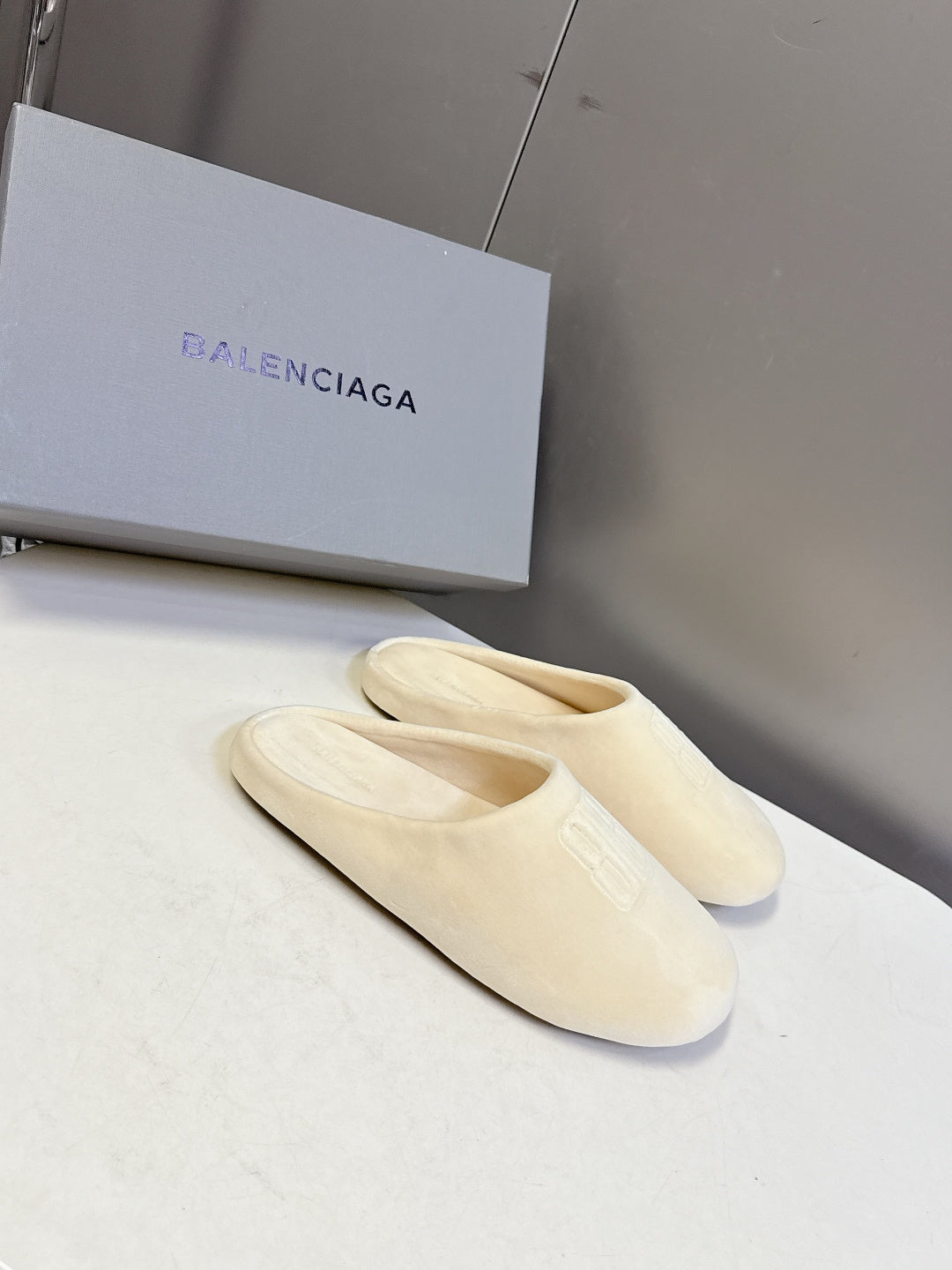 Balenciaga slide sandals, light beige, angled pair with logo footbeds