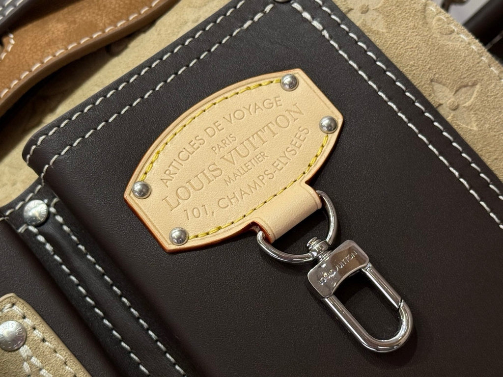 Louis Vuitton luggage tag label charm with keyring on brown leather flap, gold badge.