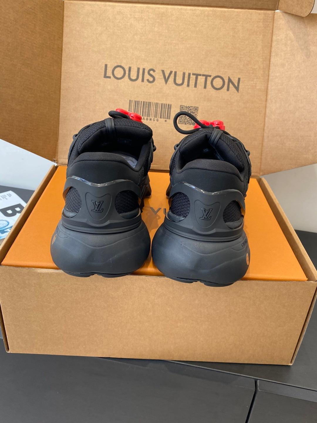 Black lace-up sneakers rear view with red LV heart pull tabs