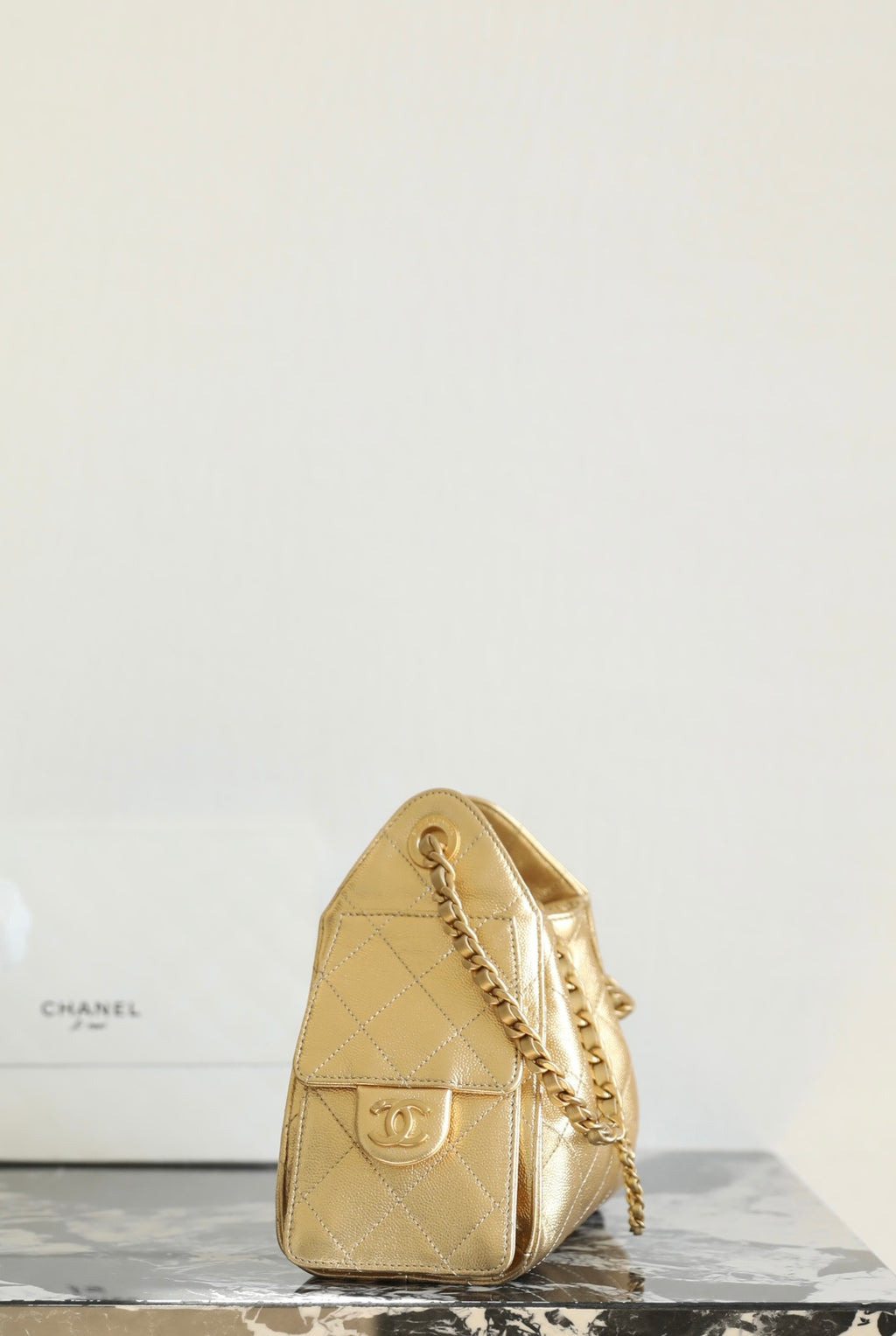 Chanel metallic-gold quilted bucket bag with chain strap and gold logo plate
