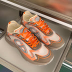 Dior unisex sneakers pair, orange laces over light orange and gray graphic design