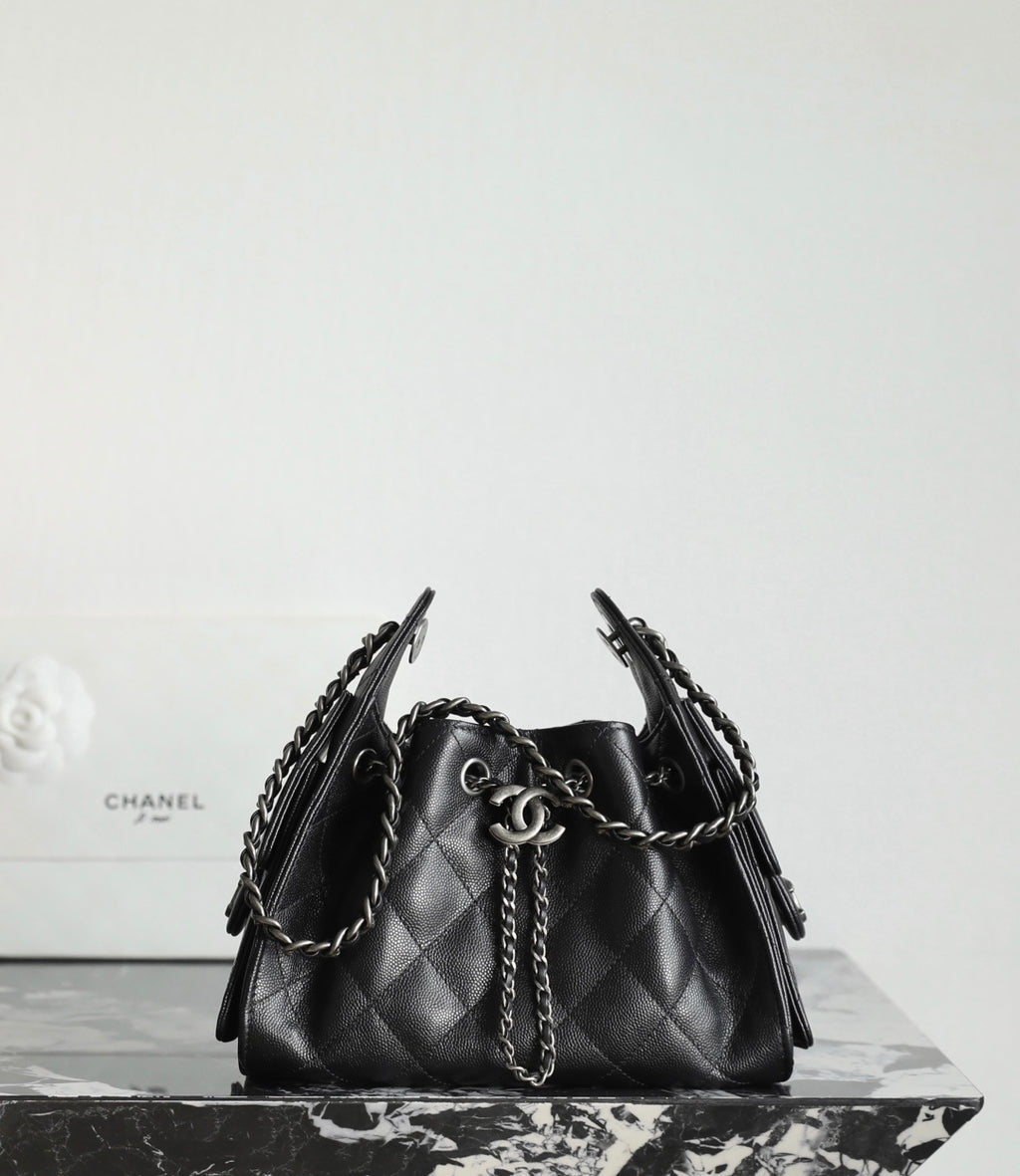 Black quilted bucket bag with chain strap handles and CC charm on the front