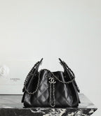 Black quilted bucket bag with chain strap handles and CC charm on the front