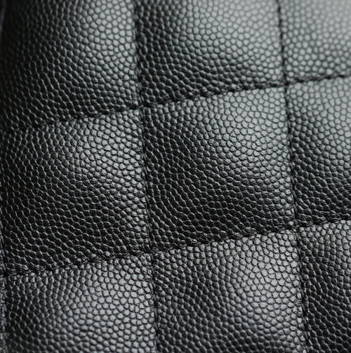 Black pebbled leather texture close-up with stitched panel seams