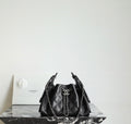Black quilted bucket bag with chain handles and CC charm at the drawstring front