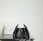 Black quilted bucket bag with chain handles and CC charm at the drawstring front