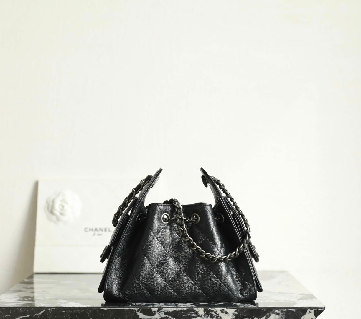 Black quilted bucket bag with chain handles and drawstring closure with CC charm