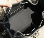 Black fabric-lined interior of a bag with stitched edge and metal chain hardware