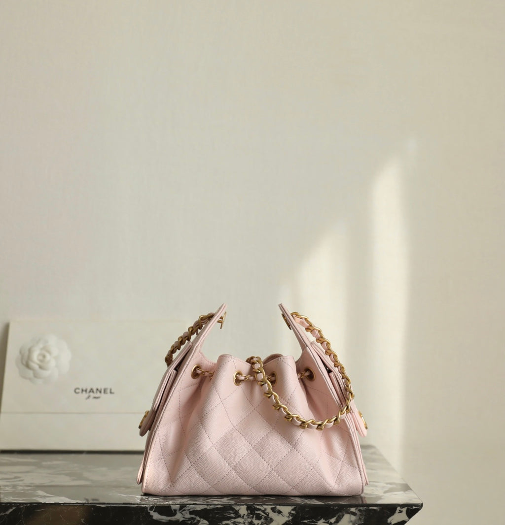 Pink Chanel drawstring bag with gold chain straps and diamond-quilt pattern