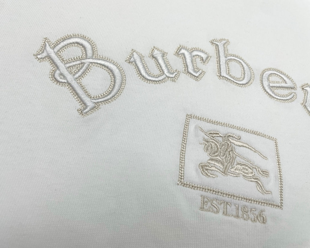 White T-shirt close-up with jeweled-style Burberry wordmark and crest