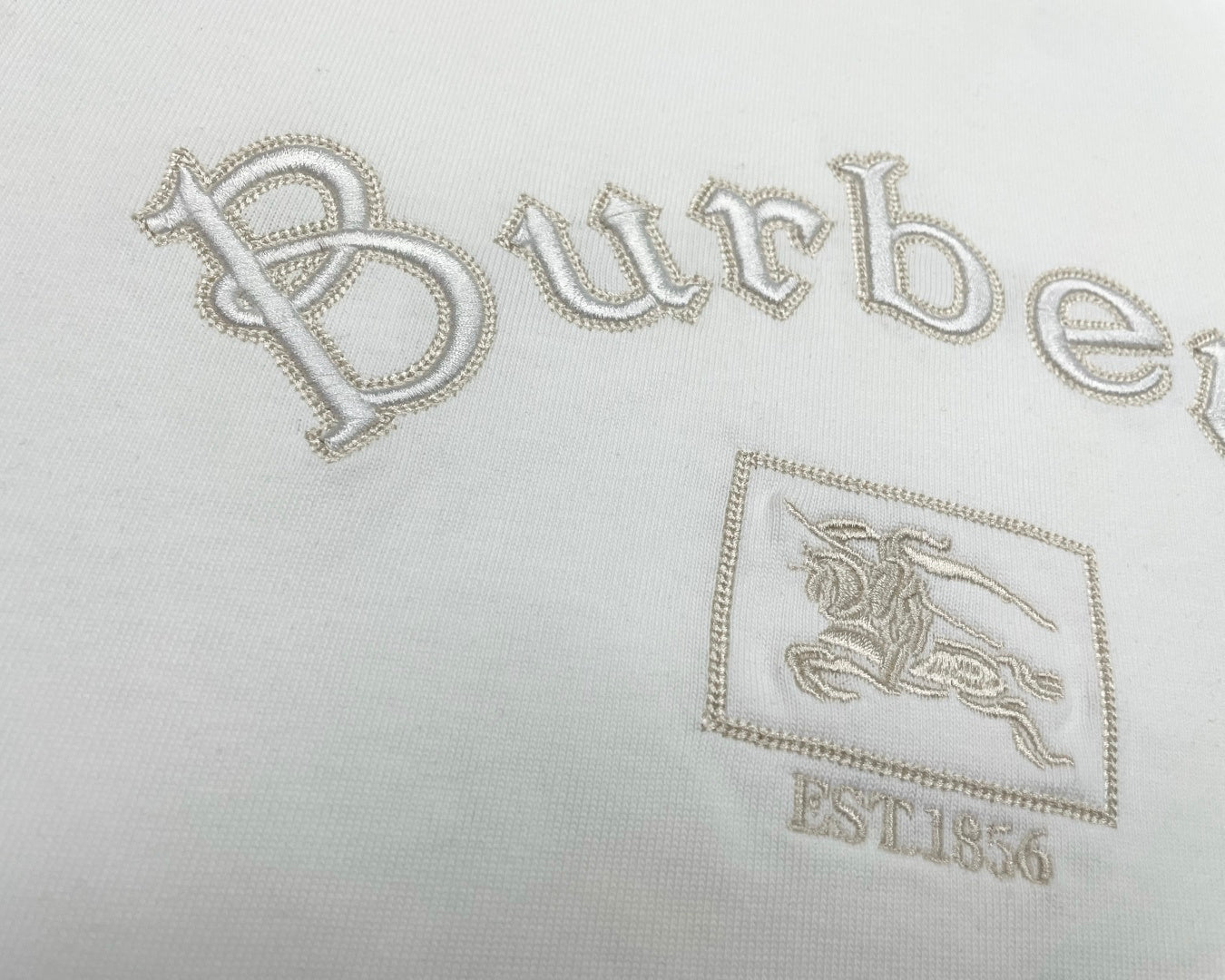 White T-shirt close-up with jeweled-style Burberry wordmark and crest