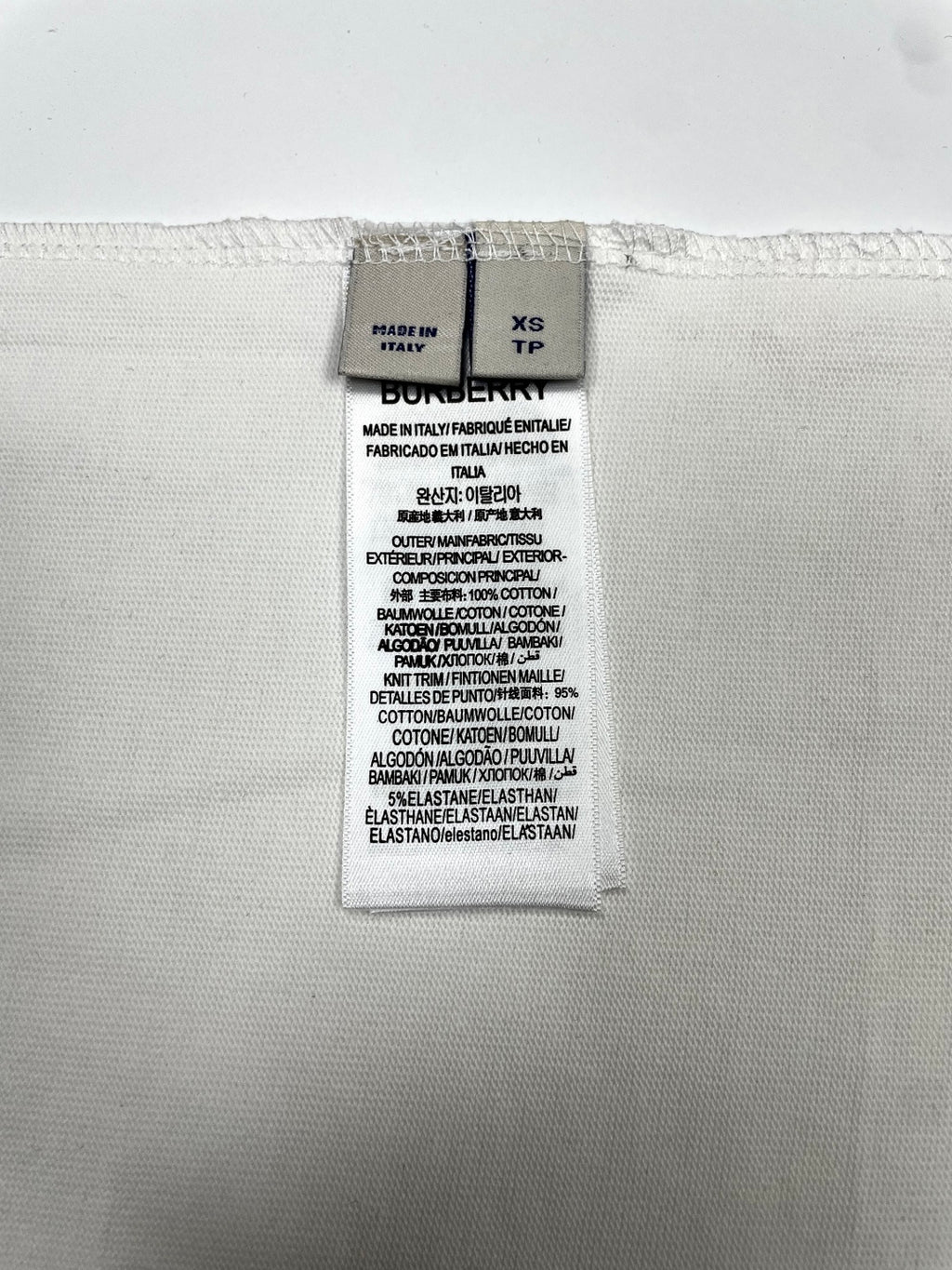 White T-shirt care and size label showing XS TP and fabric composition