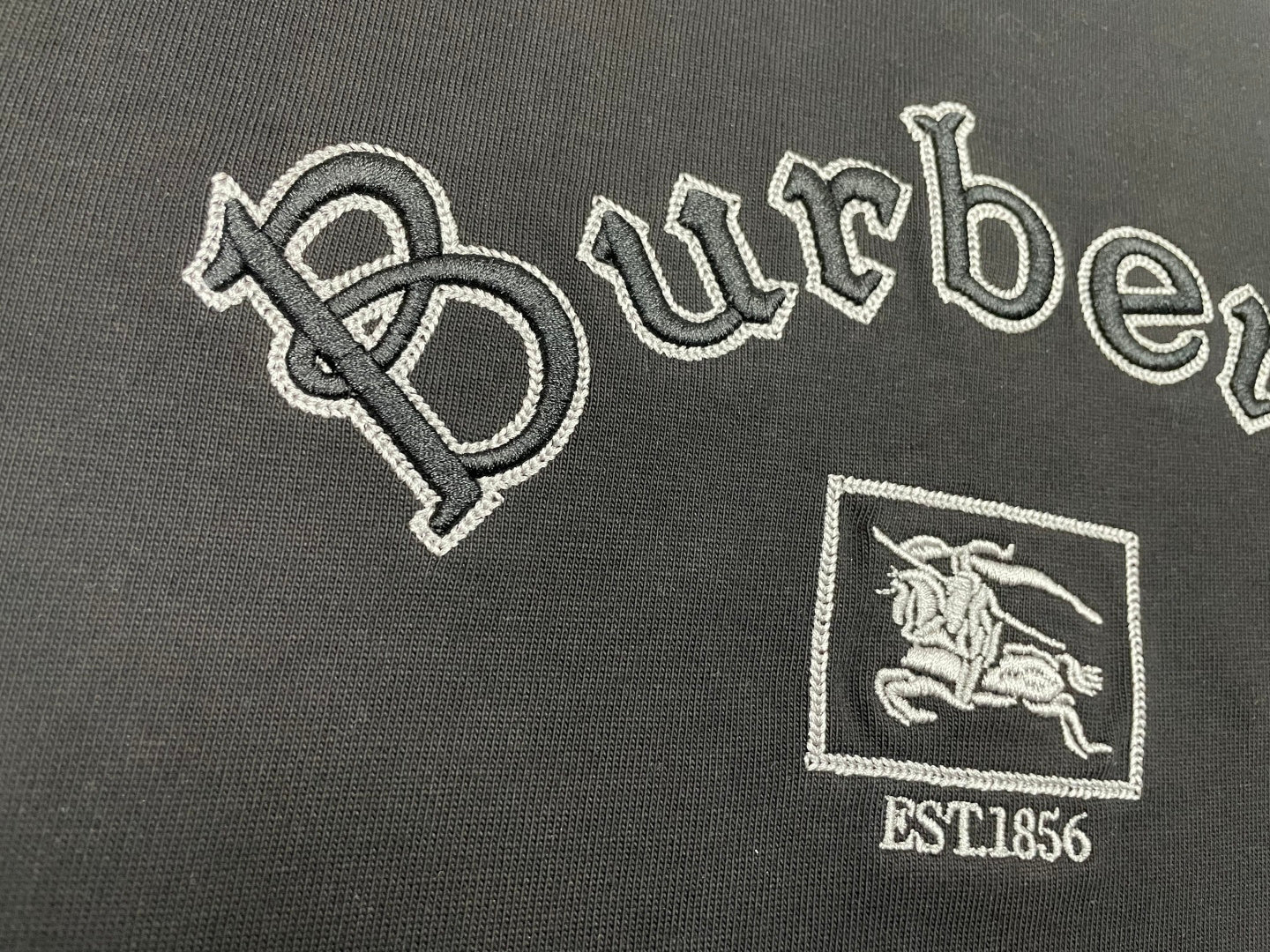Large embroidered Burberry wordmark and horse crest with EST1856 on black T-shirt.