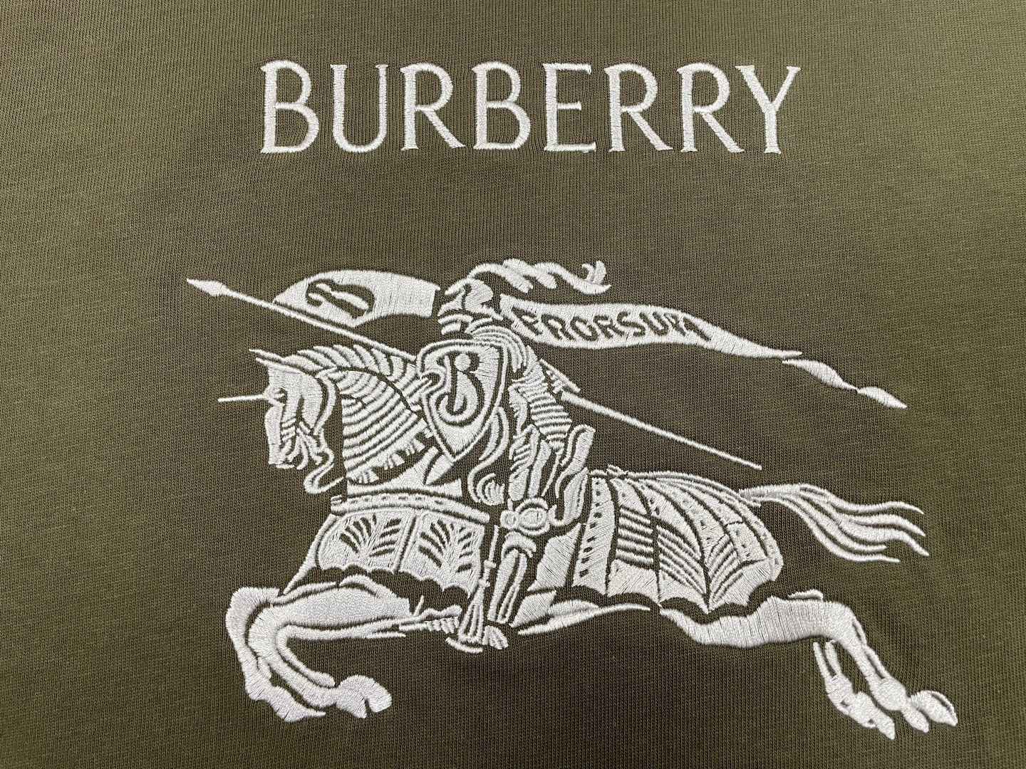 Burberry olive T-shirt with large white “BURBERRY” logo and horse rider graphic