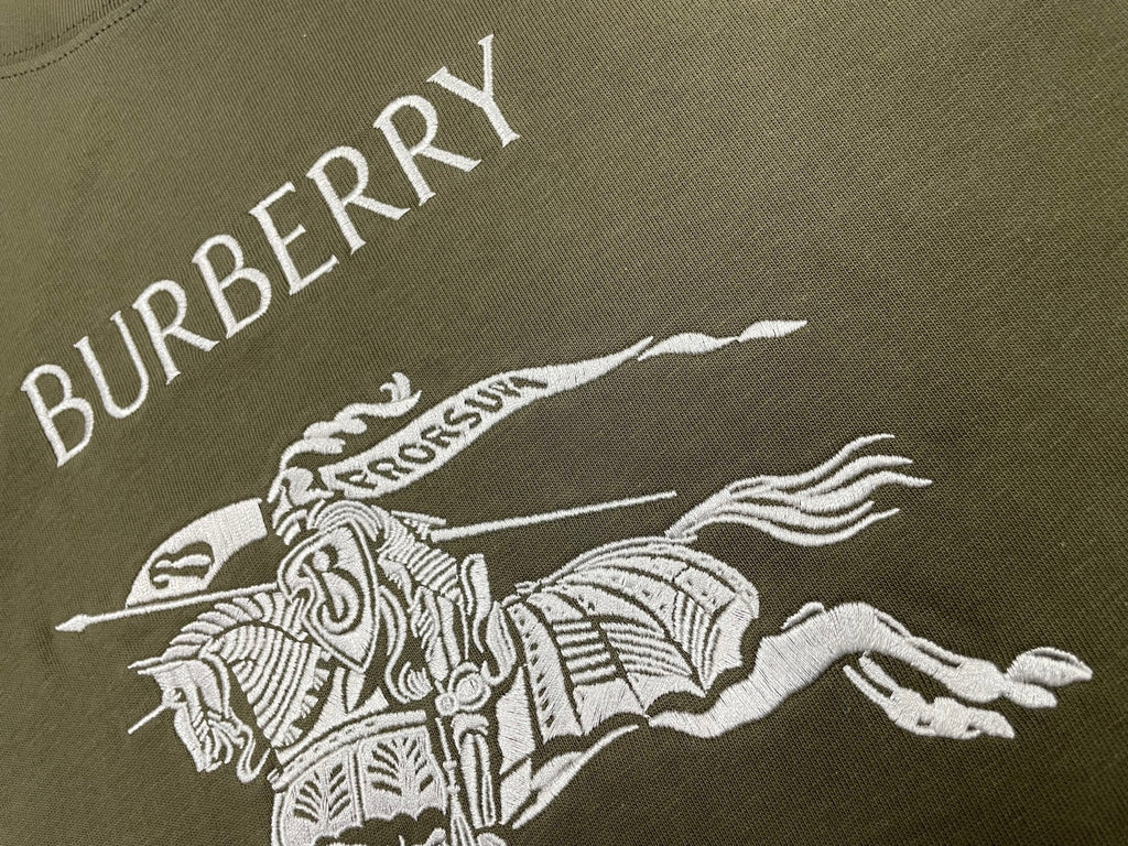 Burberry olive T-shirt with diagonal “BURBERRY” lettering and horse rider graphic