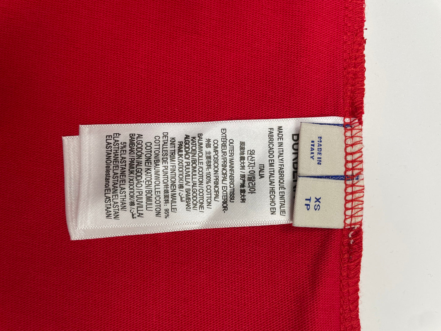Red T-shirt size label on inner hem with printed fabric and washing details