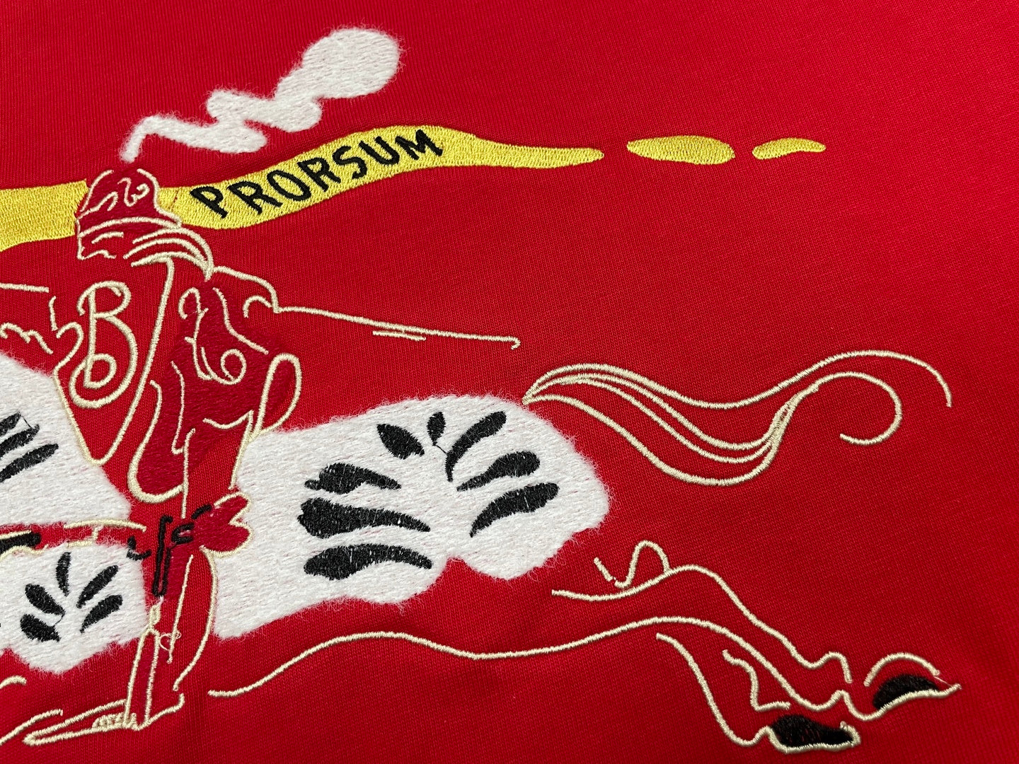 Red T-shirt fabric close-up of horse graphic and yellow streak