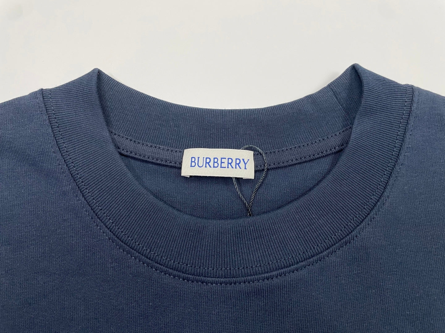 Navy crew-neck T-shirt collar with Burberry label at neckline.