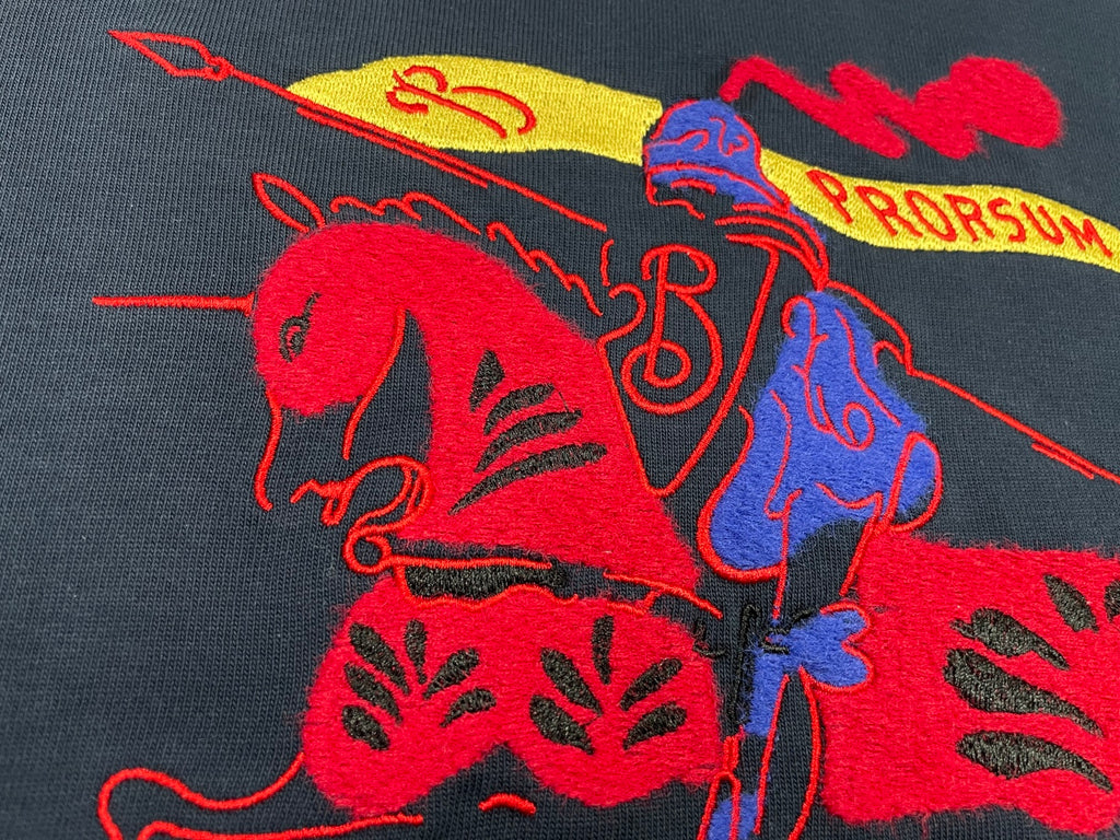 Navy T-shirt close-up of red and blue graphic horse-style print with yellow accents.