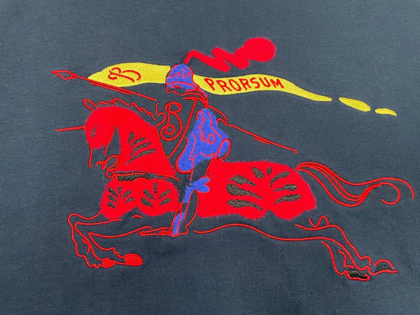 Navy T-shirt with red, blue, and yellow graphic horse-style print.