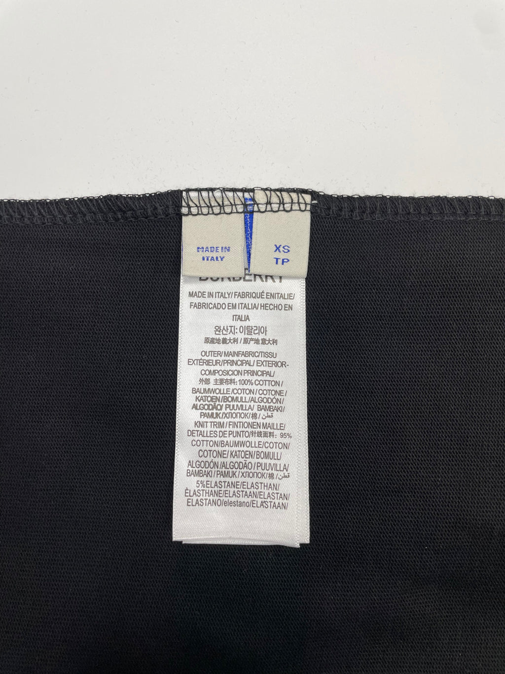 Black T-shirt size label with XS and TP, plus fabric composition text.