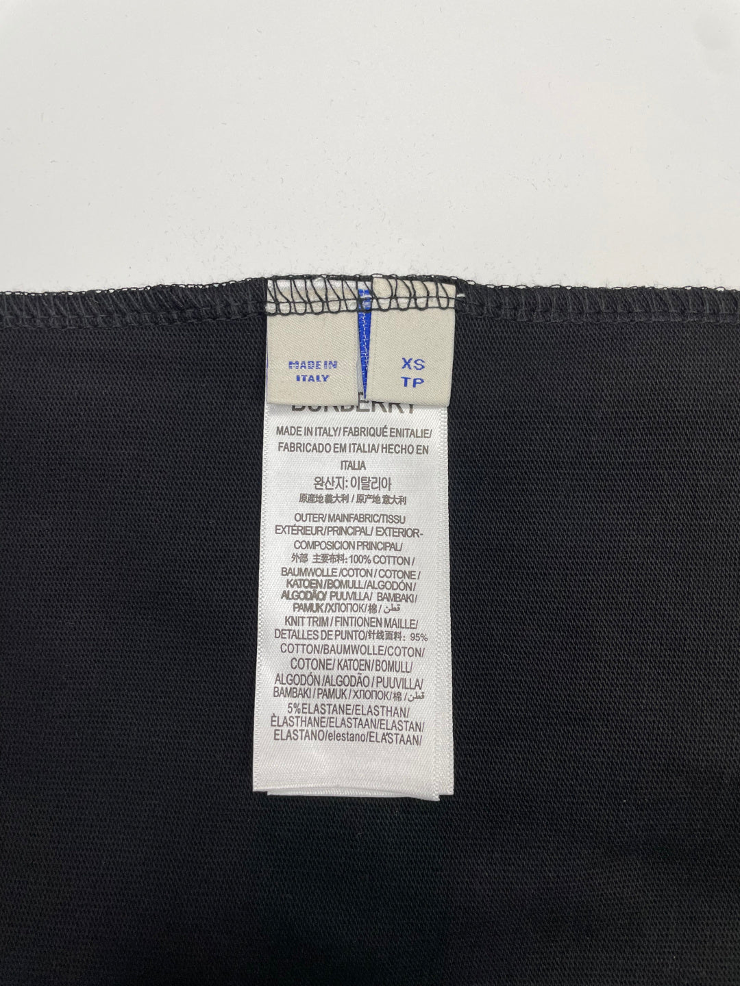 Black T-shirt size label with XS and TP, plus fabric composition text.