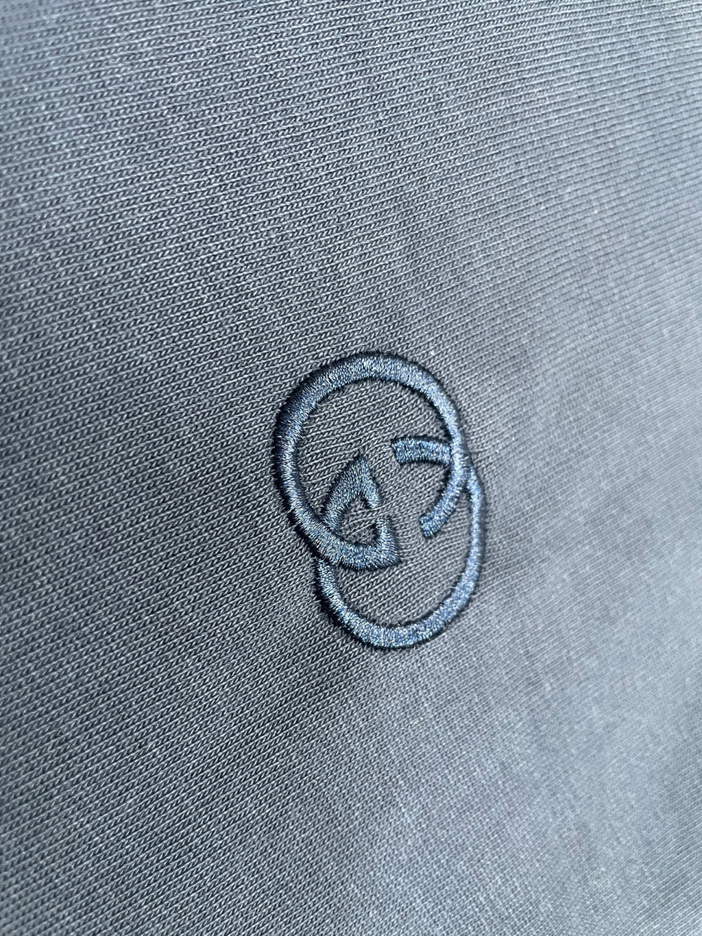 Close-up of embroidered logo on navy T-shirt fabric