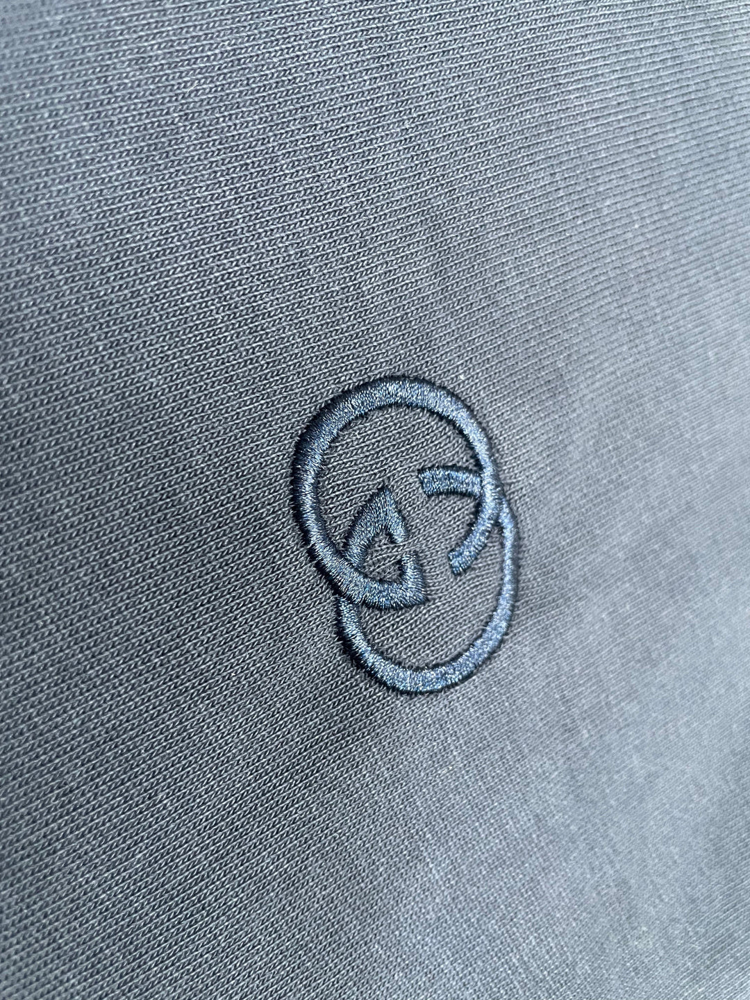 Close-up of embroidered logo on navy T-shirt fabric
