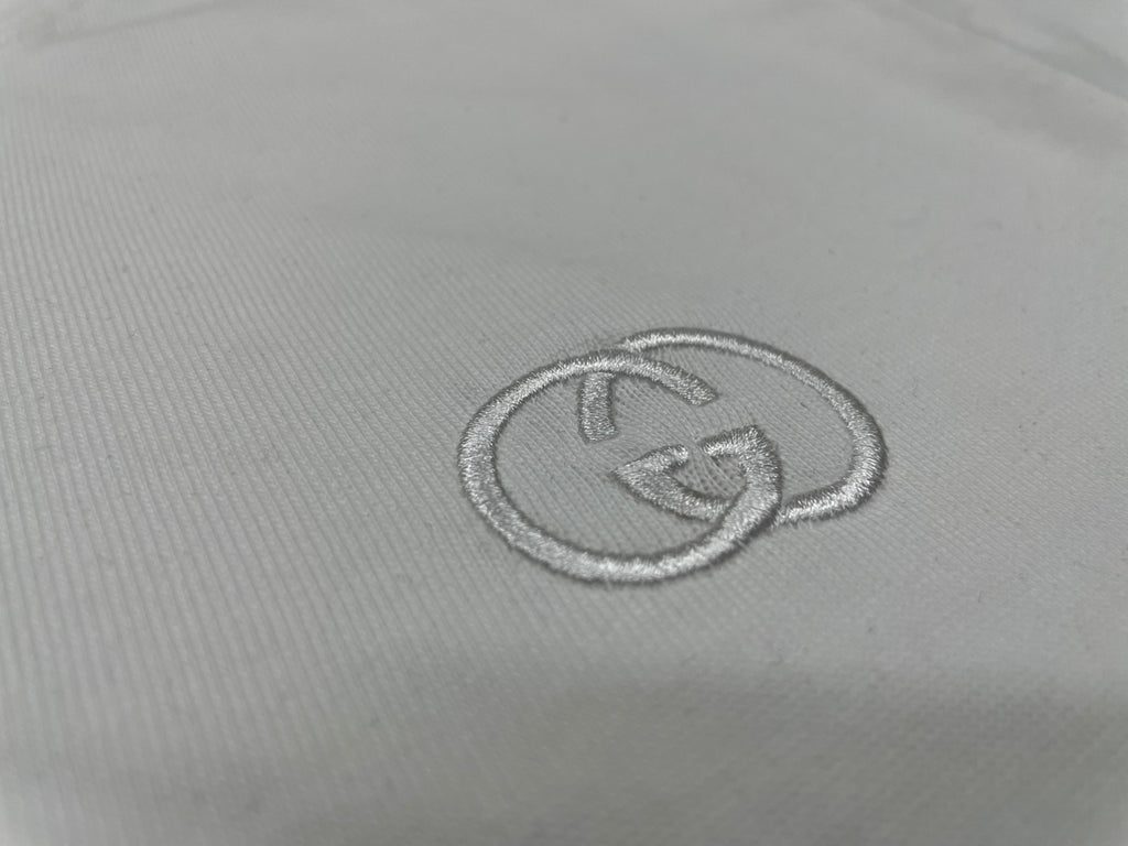 Gucci logo emblem stitch detail on white T-shirt chest