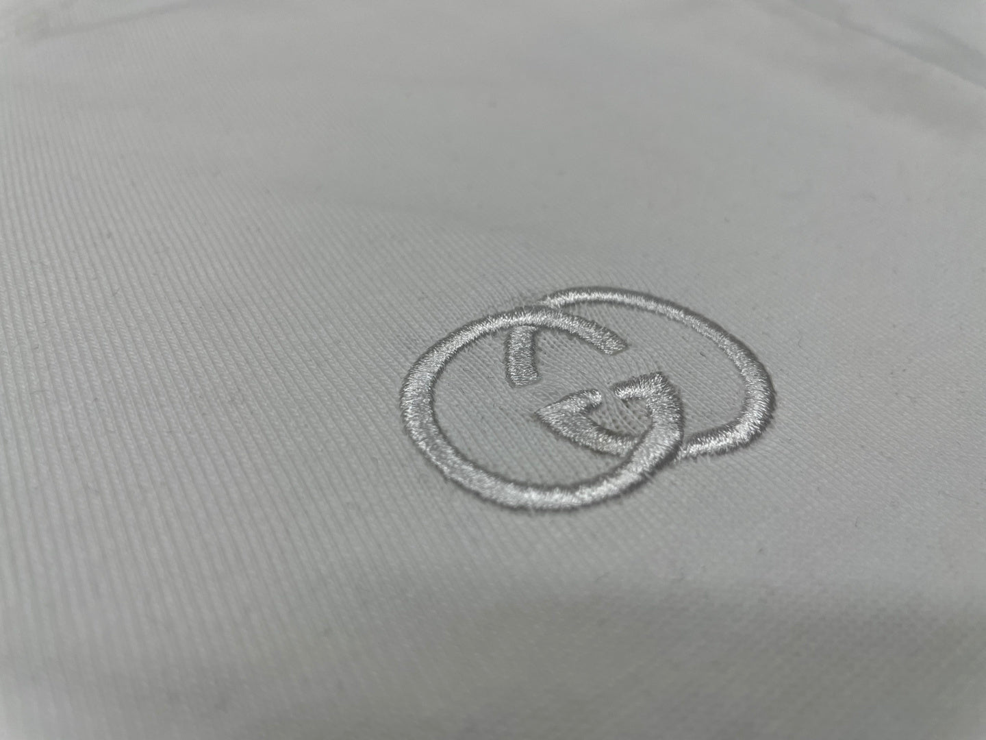 Gucci logo emblem stitch detail on white T-shirt chest